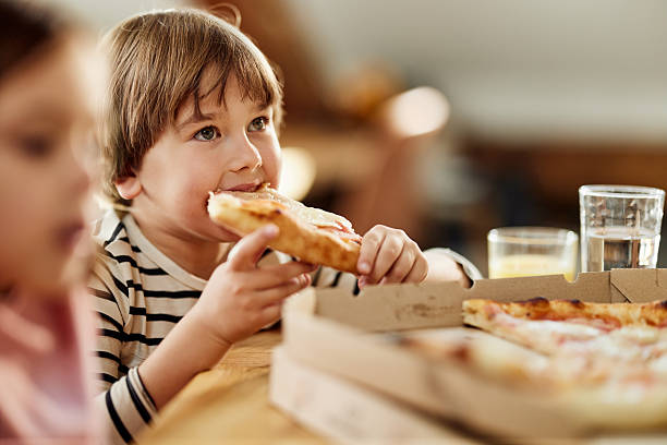 istock Cute boy eating pizza for lunch at home. 2248476973