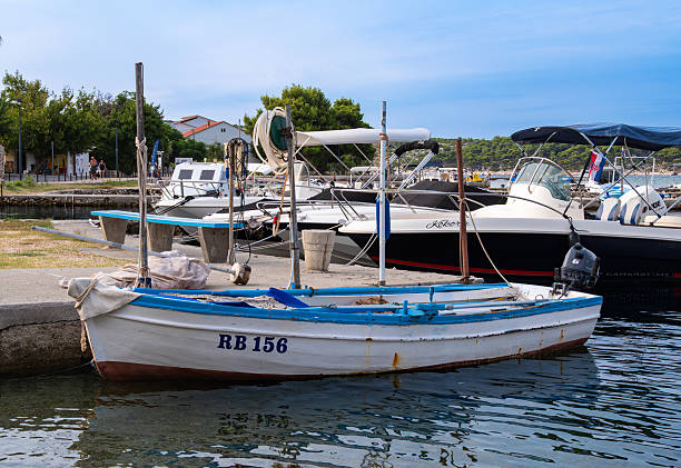 Rab, Croatia - 26 August 2025: Small fishing boat docked at a marina with other boats.