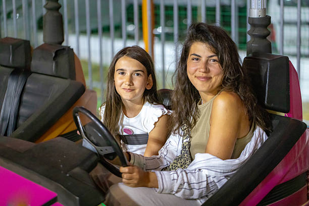Happy family having fun with dodgem cars at night fair