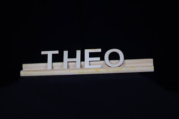 Theo traditional boy name in plain wooden letters on a tile rack isolated on a black background