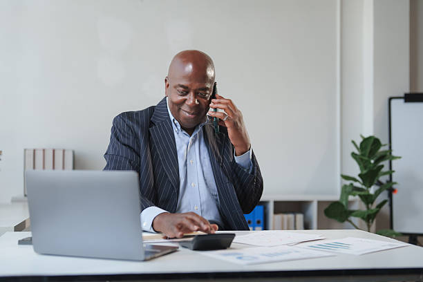 istock Senior black businessman talking on phone at office desk 2248480195