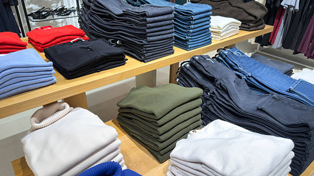 istock neatly organized store display with folded sweaters and jeans in various colors, arranged on wooden tables to create a clean and inviting shopping layout. 2248483888