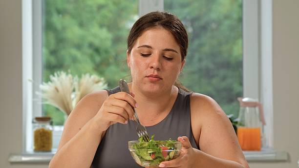 istock Woman Enjoying Fresh Salad by Window at Home 2248489841