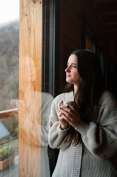 istock Young woman with mug by a window 2248490680