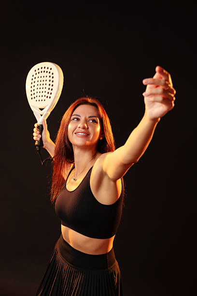 istock Woman poses confidently with a paddle racket in a dark studio setting 2248492098