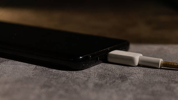 istock A smartphone connected to a braided USB cable on a textured surface, captured in warm low-key lighting. The scene highlights charging, connectivity, and everyday digital usage. 2248492628