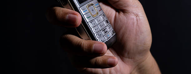Extreme close-up of worn numeric keys on an old mobile phone held in a hand, emphasizing tactile buttons and device wear. Great for themes of analog input and aging gadgets.