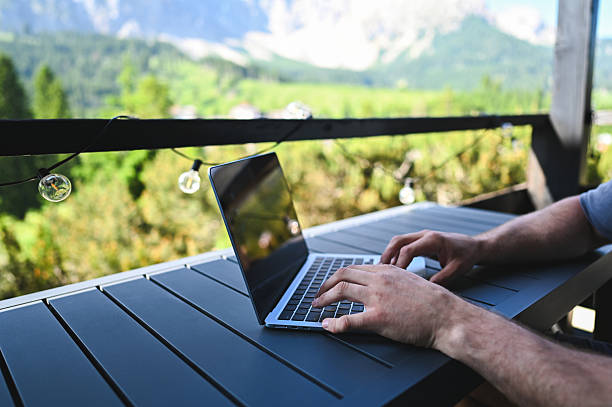 istock Man working remotely on laptop from a mountain balcony 2248500767