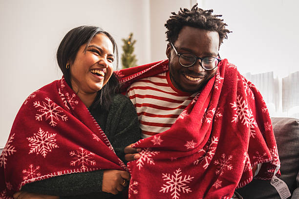 istock Diverse couple laughing sharing cozy christmas blanket 2248503500