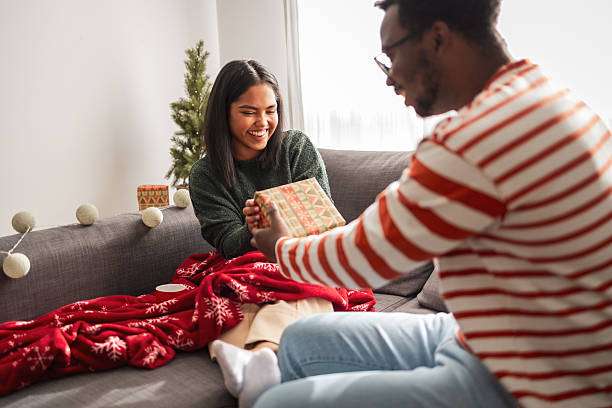 istock Couple exchanging christmas gift on sofa feeling cheer 2248503501