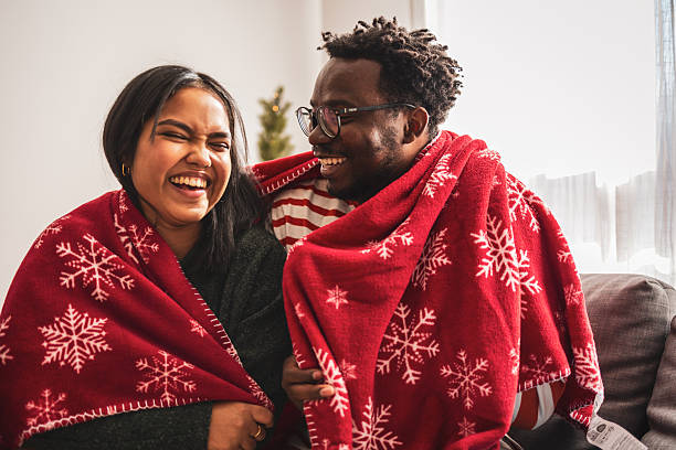 istock Happy diverse couple laughing sharing warm christmas blanket 2248503505
