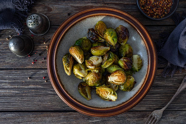 istock Baked Brussels sprouts in rustic bowl on wooden table. Top view 2248505432