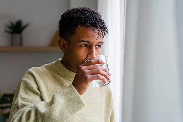istock Young man hydrating, thinking and looking out window 2248506520