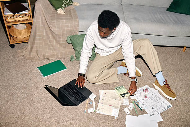 istock Young Black Man Reviewing Invoices and Bills Using Laptop on Floor 2248506787