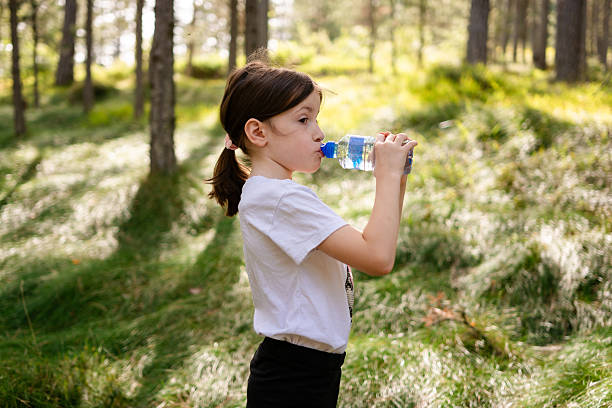 istock Girl drinking water bottle in sunny forest 2248509972
