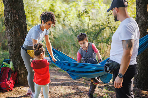 istock Man and his wife securing hammock between two trees, their children waiting to get in 2248510577