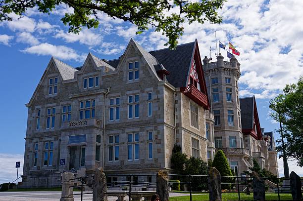 Santander, Spain – May 03, 2025: The Palacio de La Magdalena with turreted architecture and flying flags, set against a partly cloudy sky.