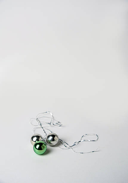 Green and silver Christmas tree balls and tinsel on a white background, space for text