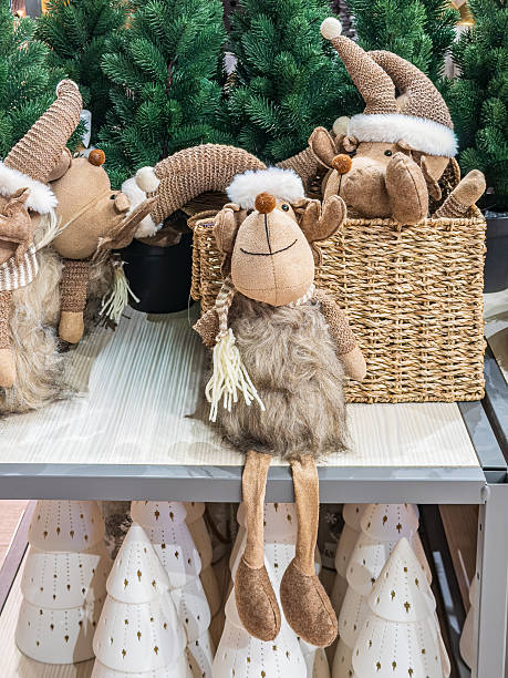 istock Cute Christmas plush decorations with reindeer and gnome figures displayed on shelves with green festive trees 2248519066