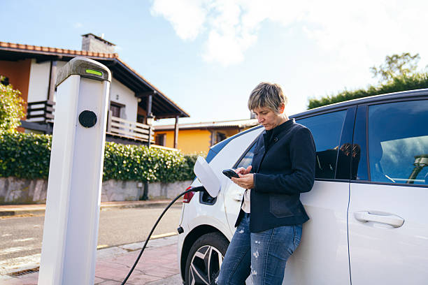 istock Woman charging electric car using smartphone at home 2248519106