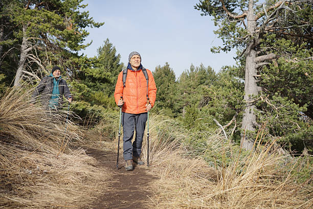 Two men practicing Nordic Walking on a mountain pathway.