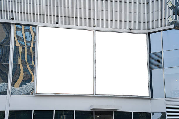 istock Mockups of two blank white billboards framed by a modern building facade, ideal for advertising 2248525622