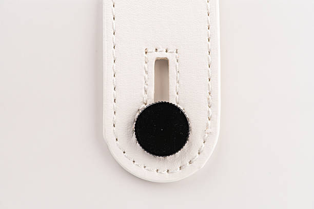 Modern mini guitar amp speaker tag, stitched leather item against light grey background, rectangular shape with rounded corners, visible stitches, hole for hangingclip attachment, even lighting, str
