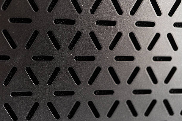 Close-up image of a modern mini guitar amp speaker with a diamond plate patterned metallic surface The texture is angular, ridged, and matte No additional objects are present Even lighting suggest