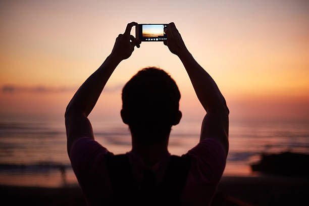 istock Man Photographing Sunset with Smartphone on Beach 2248534163