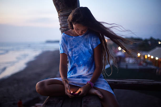istock Woman Sitting Outdoors Using Smartphone at Sunset Beach 2248534602