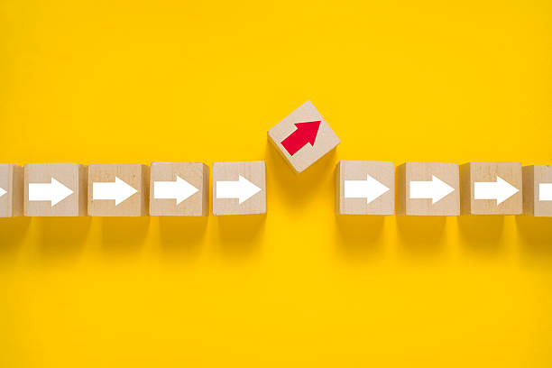 istock wooden blocks with white arrows and one different direction red arrow isolated on yellow background. leadership concept 2248537278