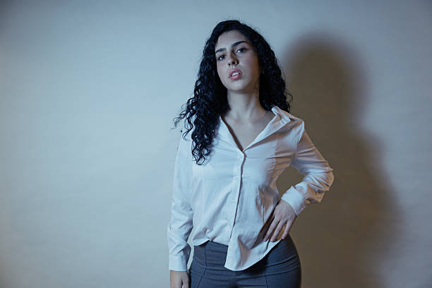Young woman standing confidently in a studio, showcasing professional and business attire