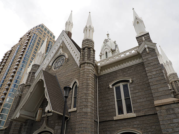 Salt Lake City, UT - September 20, 2025: Low angle view showing the historic LDS Assembly Hall contrasting with a modern, curved glass residential tower.