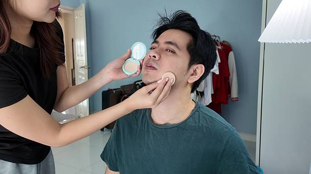 istock A woman is helping a man apply makeup 2248539203
