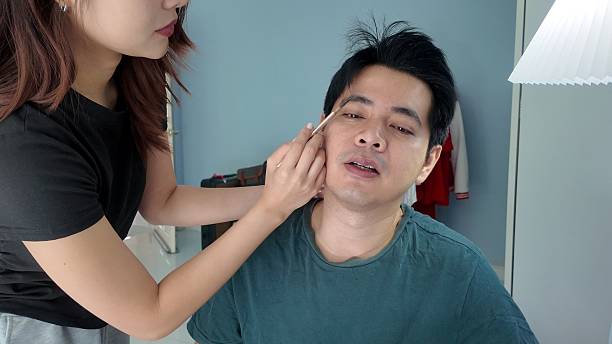 istock A woman is applying makeup to a man's face 2248539205