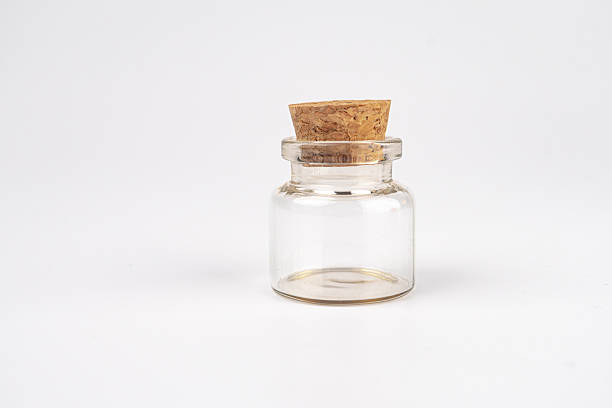 istock Clear glass jar with amber liquid, stoppered placed on a plain surface under soft light Minimalistic style. m 2248539294