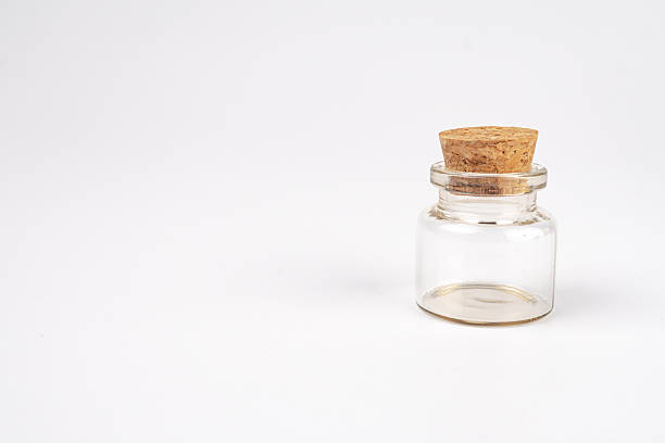 Clear glass bottle with amber liquid, centered on a gray background, tilted slightly to the side, no visible text or branding, even lighting in a controlled indoor environment