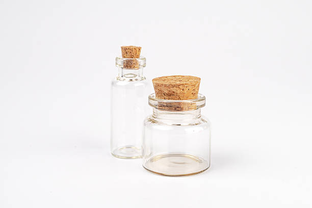 istock Two glass bottles with cork stoppers on a neutral surface, differing slightly in height and width, containing translucent liquids or air Natural craggy corks fitted securely Ambient indoor lighting 2248539311