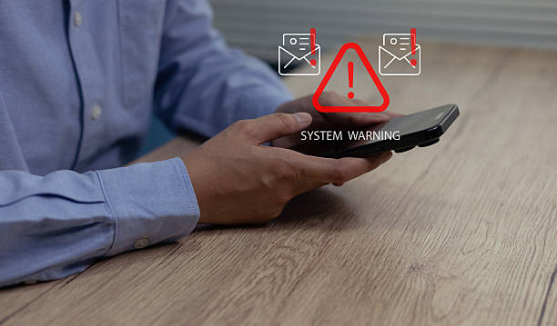 istock Person holding smartphone with digital system warning alert displayed above the device,Concept of cybersecurity risk, mobile malware threat, data breach notification, email security warning message 2248539376