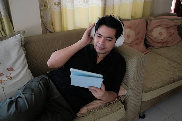 istock A man is sitting on a couch with a tablet in his lap 2248539623