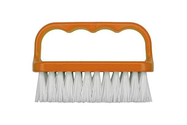Orange handheld scrub brush with white bristles is isolated.