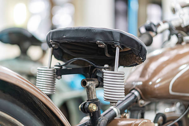 istock Vintage motorcycle seat, black, smooth texture, slight curve, metallic suspension system or equipment, cylindrical shape, coiled springs, potential shock absorption, indoor setting with artificial li 2248541689