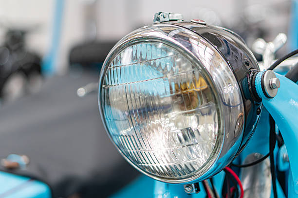 istock Close-up of vintage blue motorcycle undergoing maintenance in a workshop, with focus on polished chrome headlight reflecting light Other visible parts include handlebars and possibly engine Tools a 2248541930