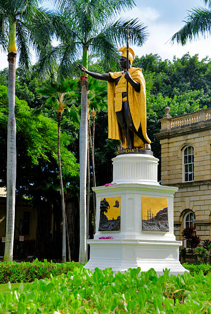 Waikiki, Honolulu, Oahu, Hawaii, USA: the King Kamehameha Statue, a 18-foot bronze sculpture depicting the king extending his hand in aloha while wearing the Sacred Sash of Liloa, stands in front of Ali'iolani Hale (Hawaii State Supreme Court). Commissioned in 1878 by King David Kalakaua to honor Kamehameha I's unification of the Hawaiian Islands in 1810, it was sculpted by Thomas R. Gould in Florence, Italy, and dedicated in 1883. A symbol of Hawaiian monarchy and leadership, it is ceremoniously draped with flower leis on June 11 for Kamehameha Day.