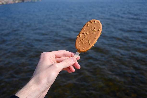 Chocolate nut ice cream against a lake backdrop under clear sky.