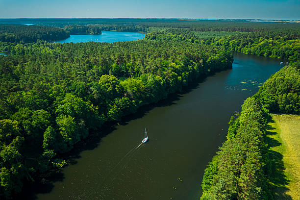 istock Small white boat sailing on large river among forests, Poland 2248542882