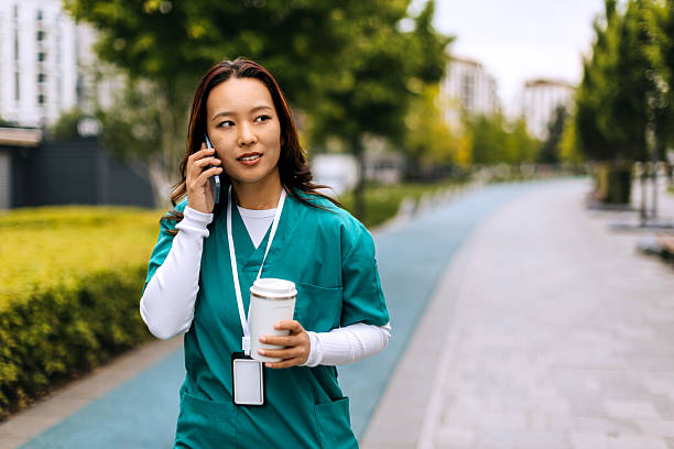 istock Smiling female nurse talking on smart phone while walking outdoors 2248542916