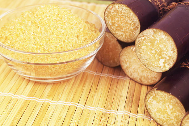 Brown sugar in  bowl and sugar cane sticks on bamboo background