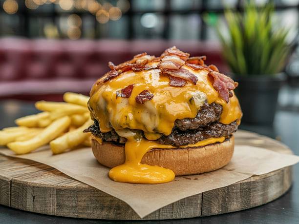 A delicious cheeseburger topped with bacon and melted cheese, served with fries on a wooden board.