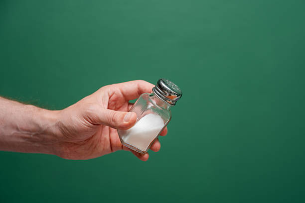 A Hand Holding Small Glass Salt Shaker